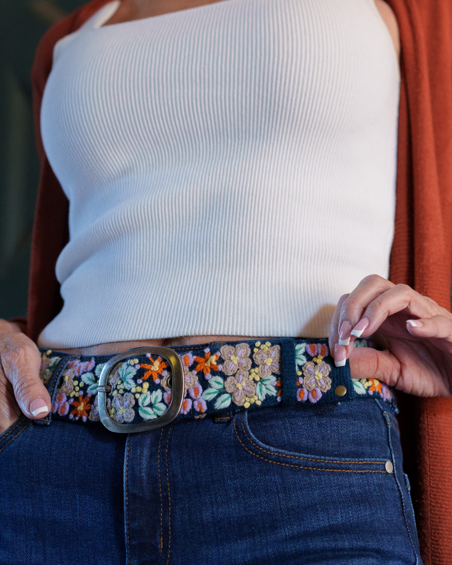 Deep navy wool belt with dimensional lavender, orange, green, cream, and yellow floral embroidery and a lead-free metal buckle.