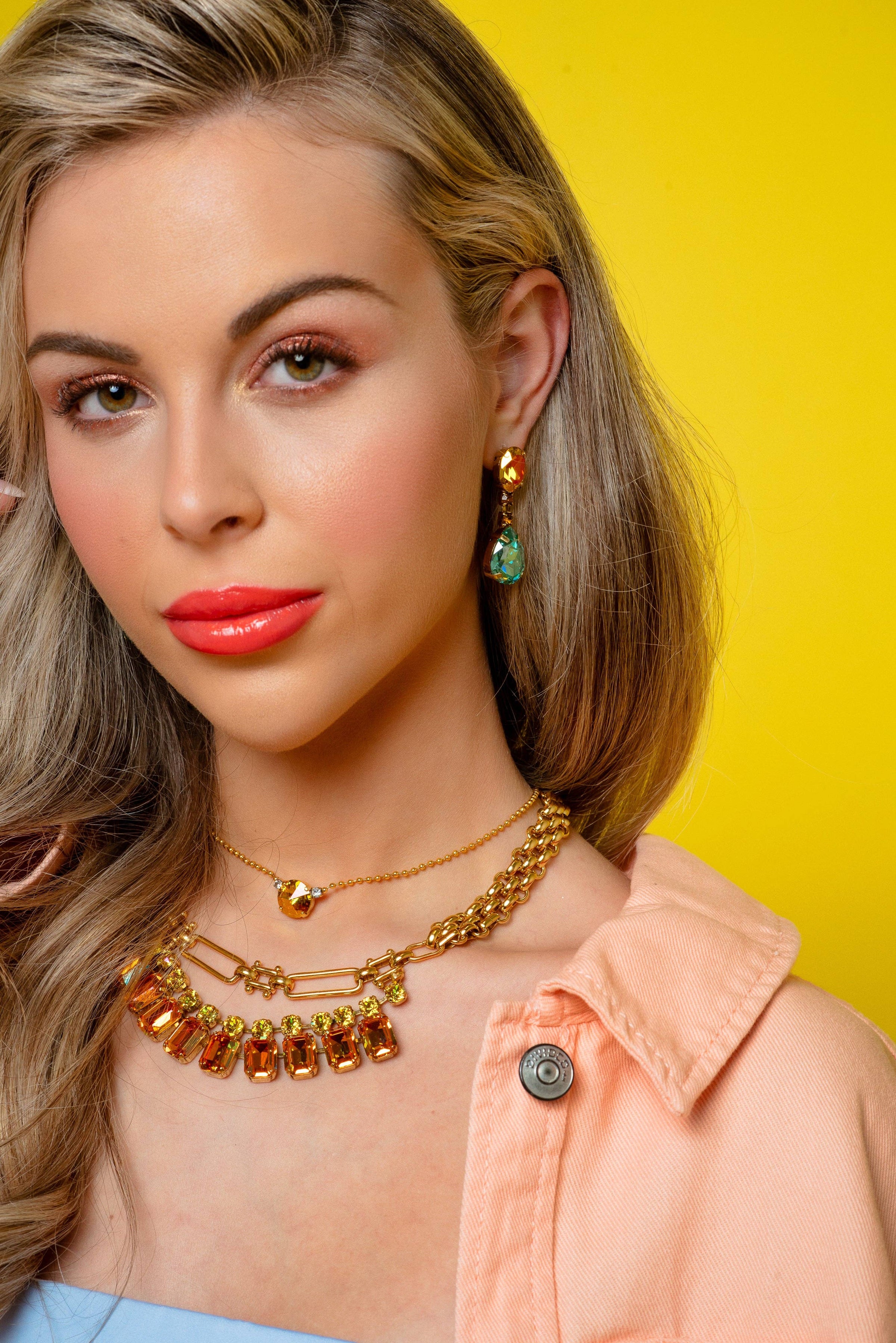 Woman wearing gold jewelry against a yellow background