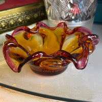Decorative glass item with a purple and amber design on a white surface.