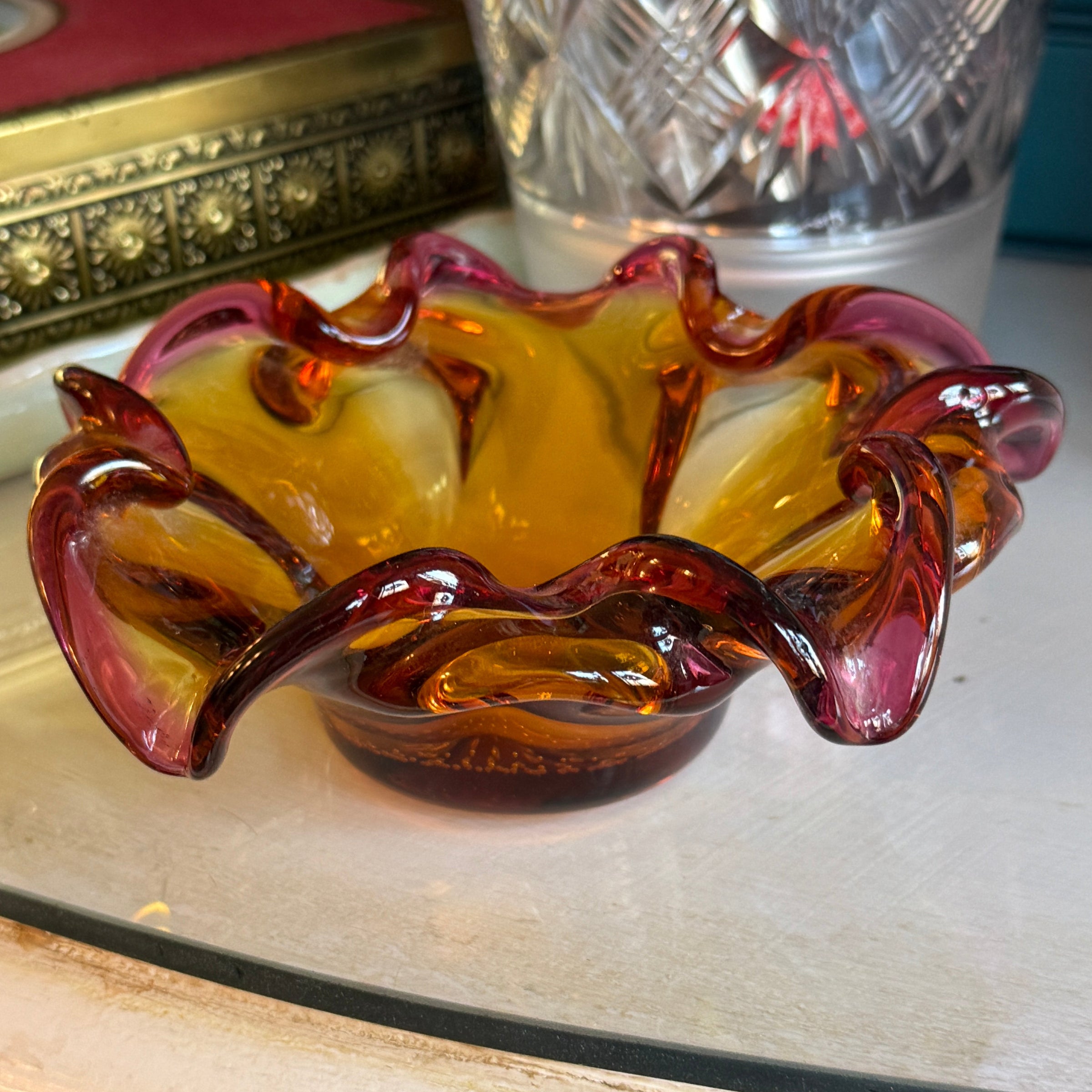 Decorative glass item with a purple and amber design on a white surface.
