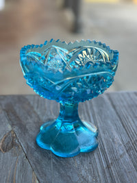 Blue glass compote on a wooden surface with a blurred background