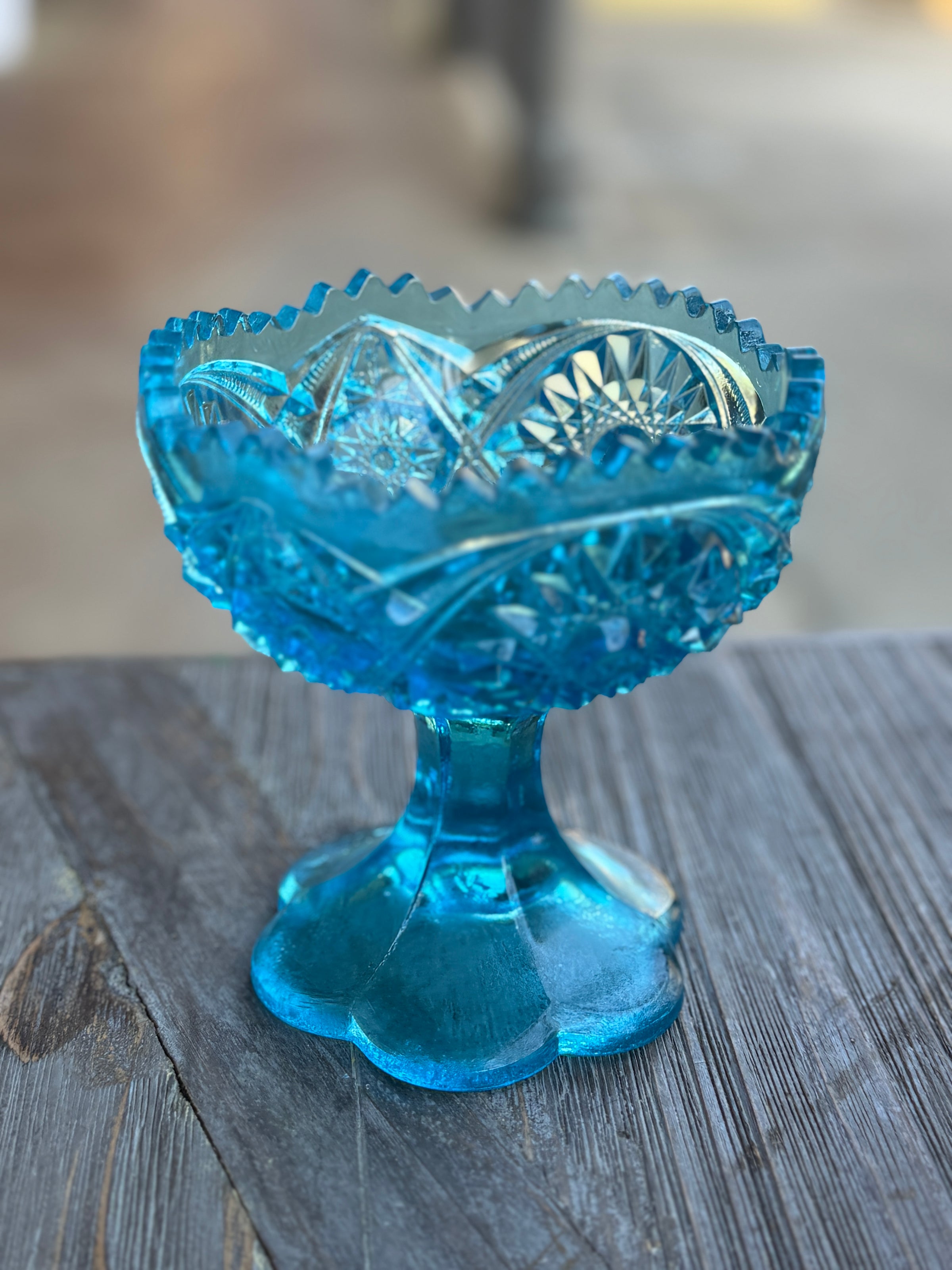 Blue glass compote on a wooden surface with a blurred background
