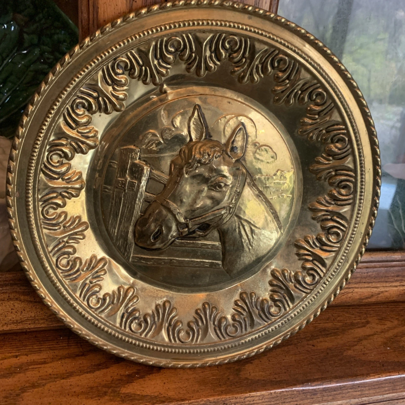 Decorative brass plate with engraved design on a wooden surface
