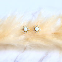Gold earrings with white stones on a fur surface