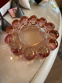 A vintage pink glass party platter with a scalloped rim, displayed on a white table.