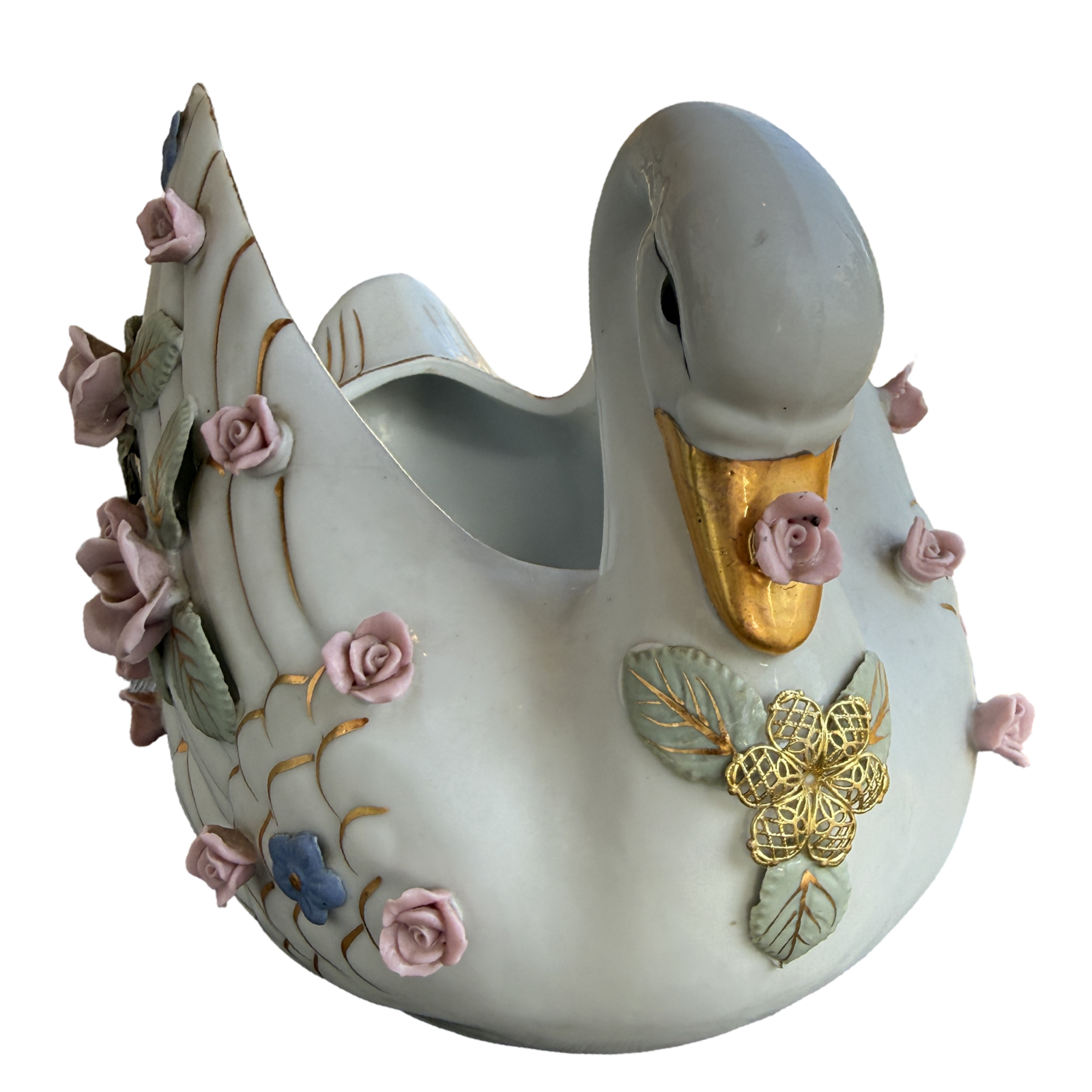 A decorative ceramic swan-shaped planter with a glossy off-white glaze, featuring a gold-painted beak, gold and green leaf details, and pink roses with blue accents on its body and tail.