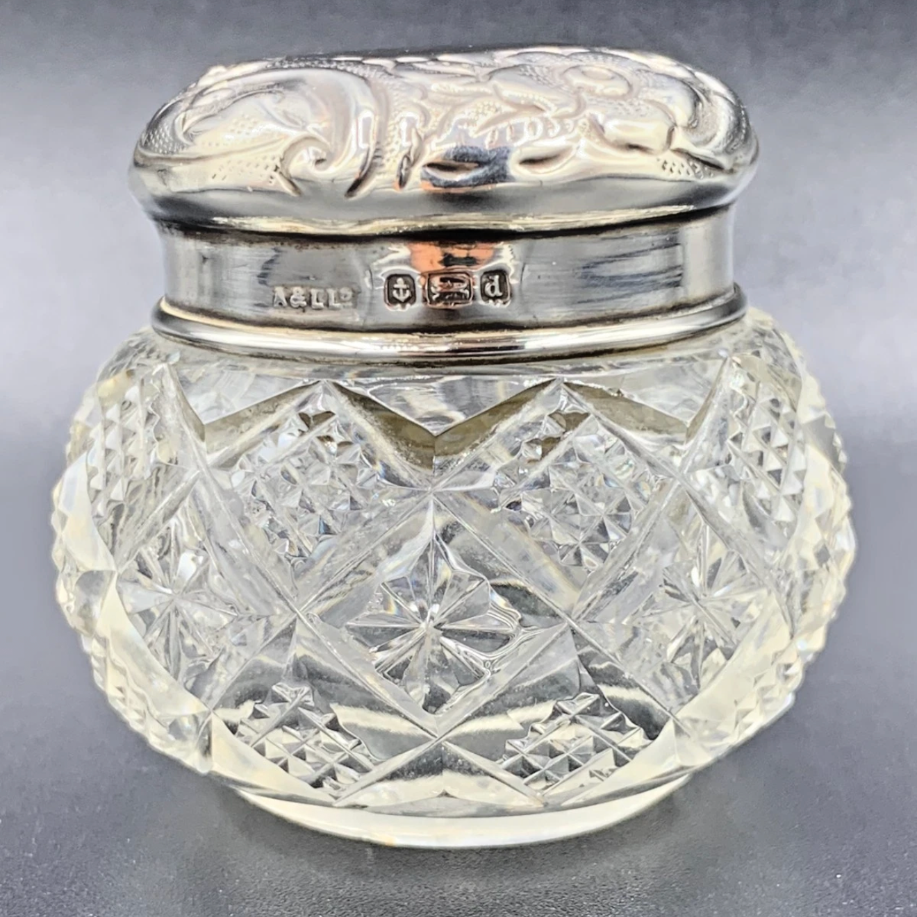 Decorative glass jar with silver lid on a gray background