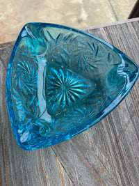 Blue glass trinket dish with intricate patterns on a wooden surface