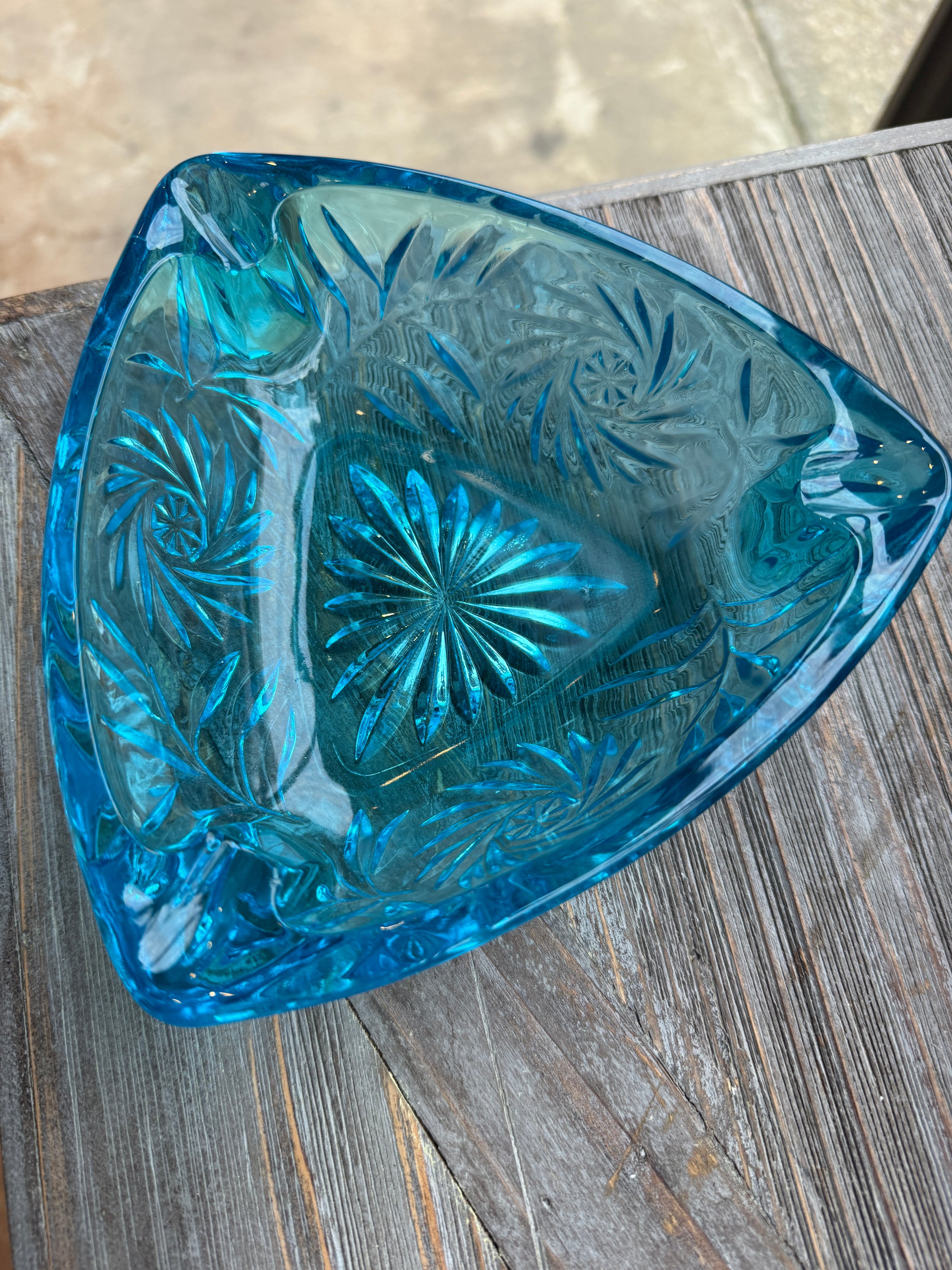 Blue glass trinket dish with intricate patterns on a wooden surface