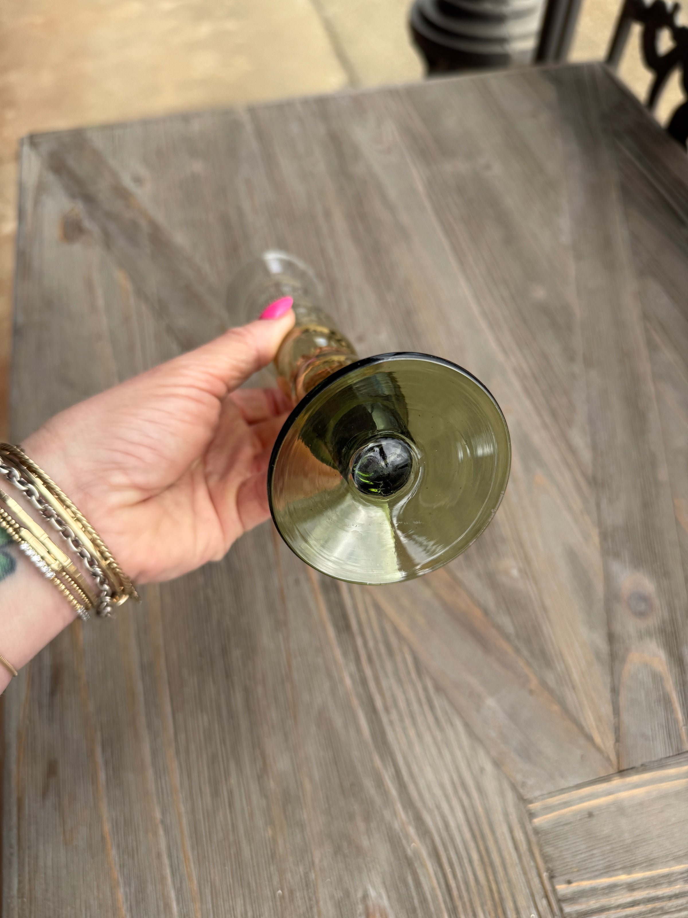 Hand holding a gold and black object against a wooden surface