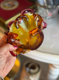 Hand holding a glass with amber-colored liquid against a blurred background