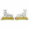 Two ceramic dalmatian dog figurines on green bases with gold accents against a white background.
