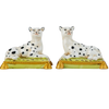 Two ceramic figurines of dogs on stands with a white background