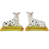 Two ceramic figurines of dogs on stands with a white background