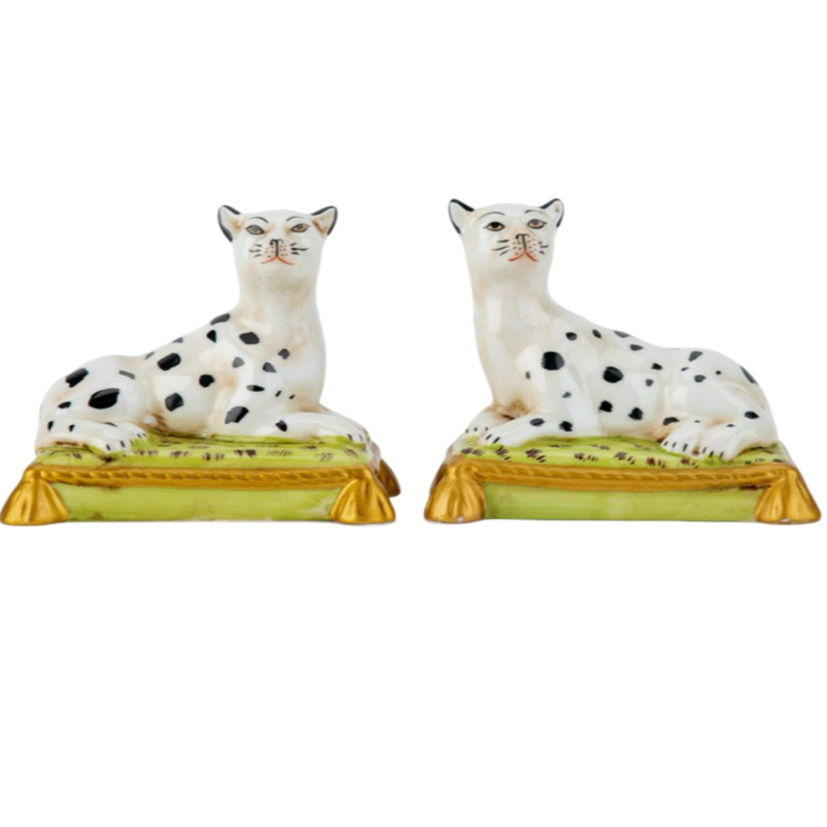 Two ceramic figurines of dogs on stands with a white background