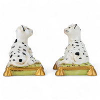 Two ceramic dog figurines with black spots on a white background
