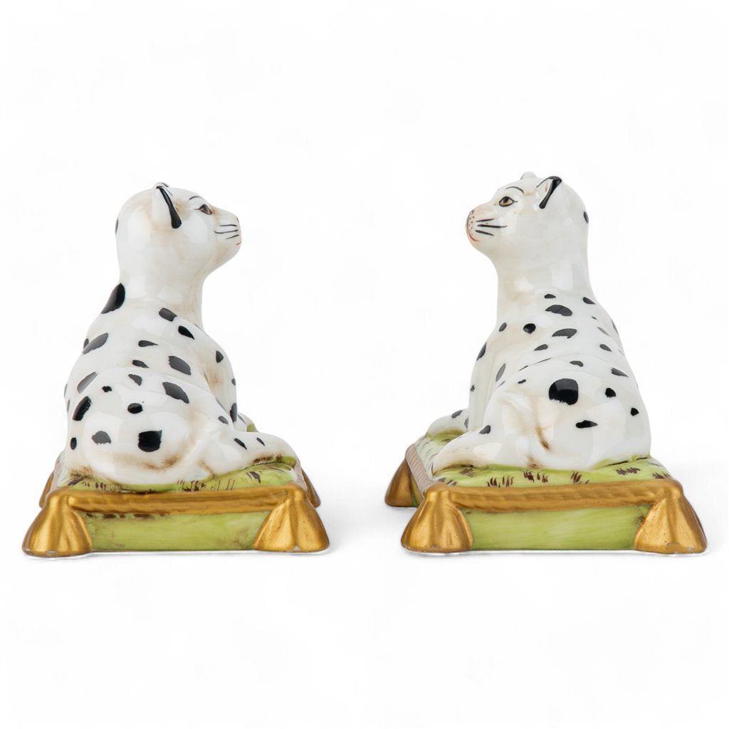 Two ceramic dog figurines with black spots on a white background