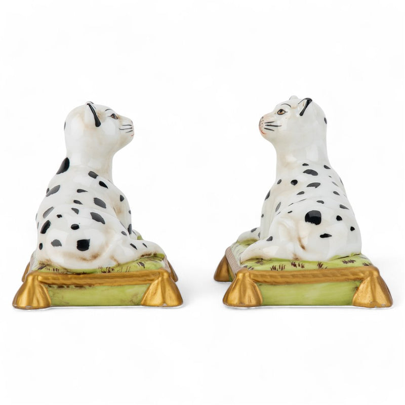 Two ceramic dog figurines with black spots on a white background