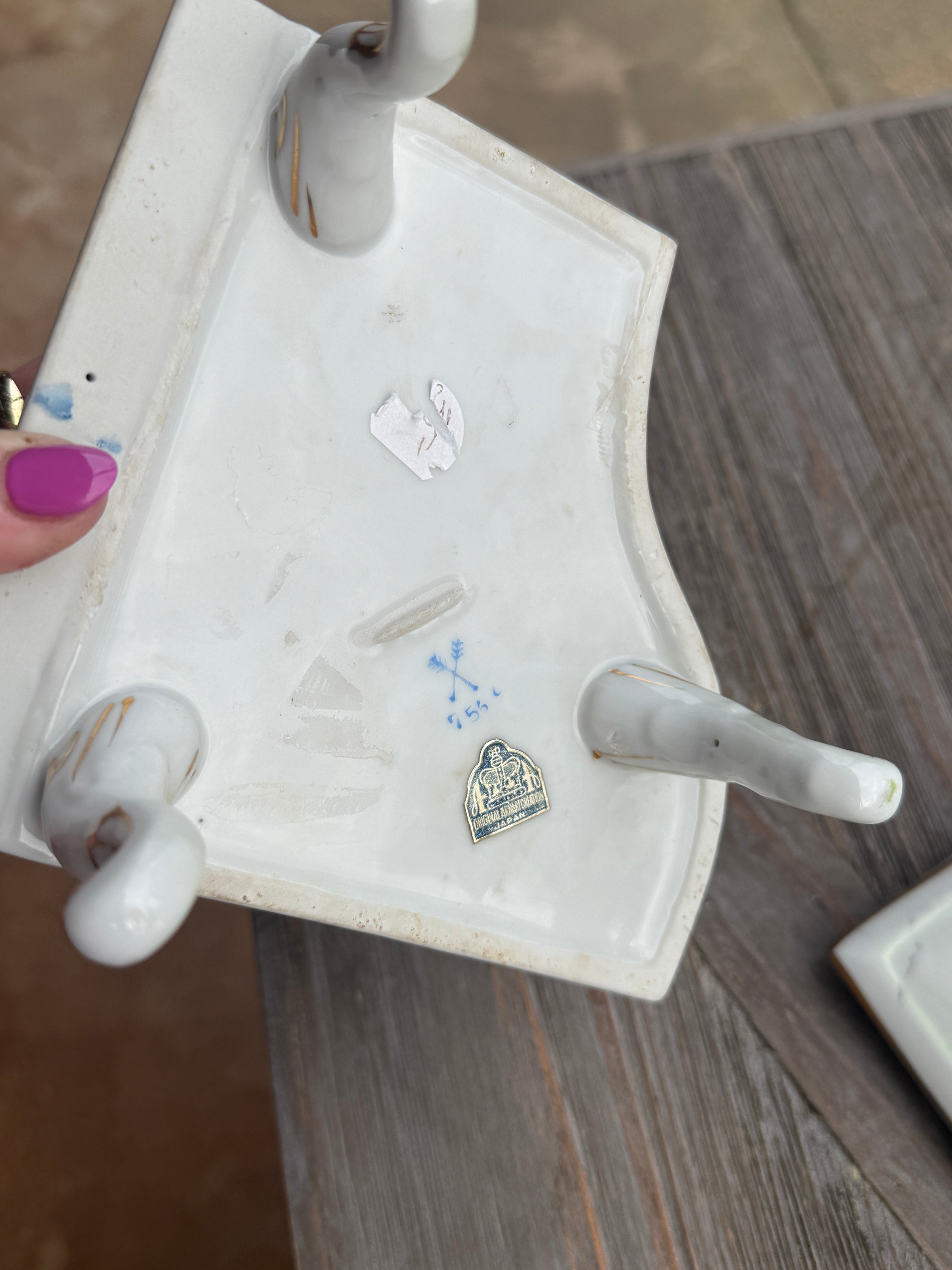 Small white jewelry stand with various silver charms on a wooden surface