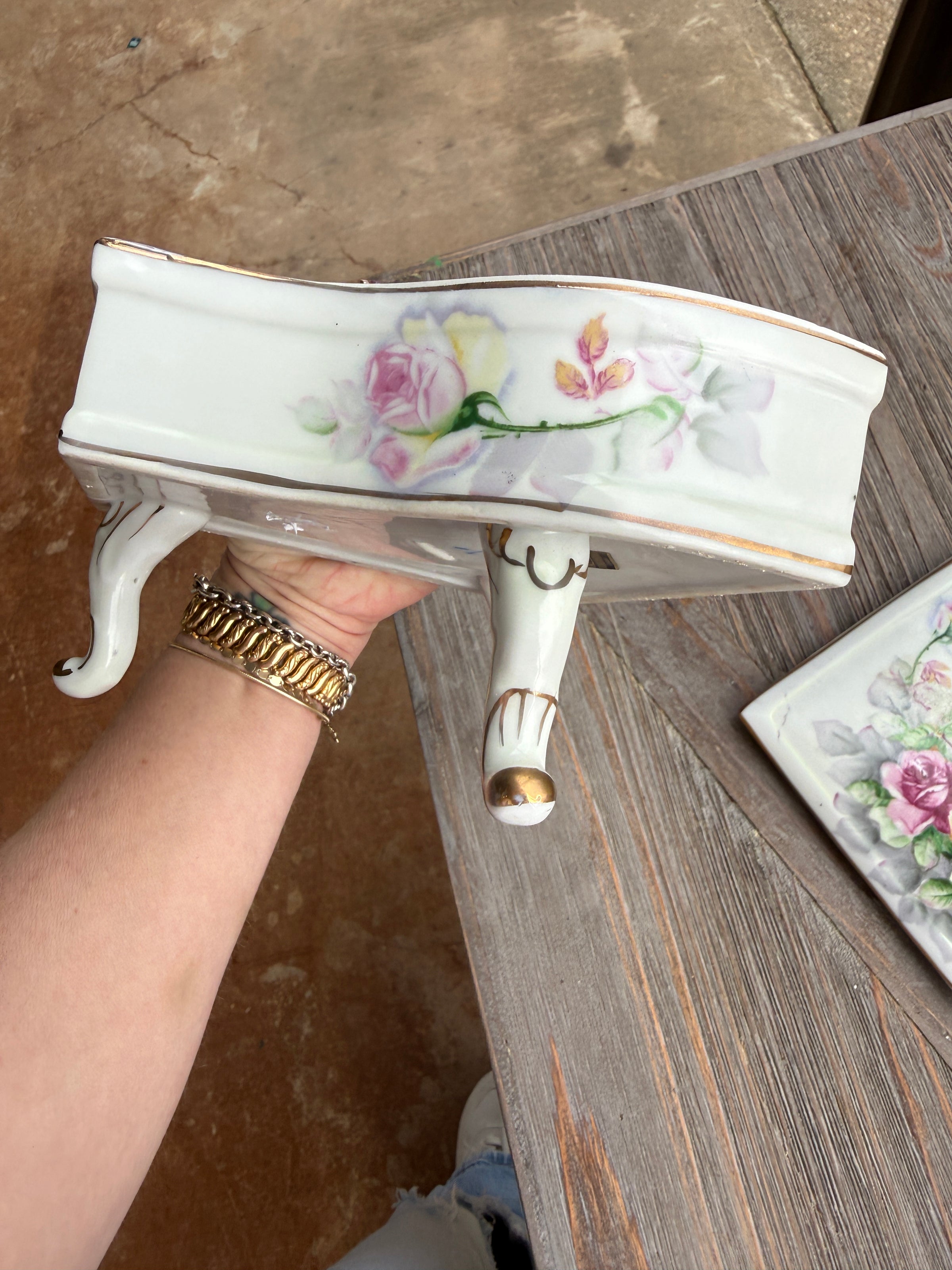 Decorative ceramic bowl with floral patterns held by a hand on a wooden surface.