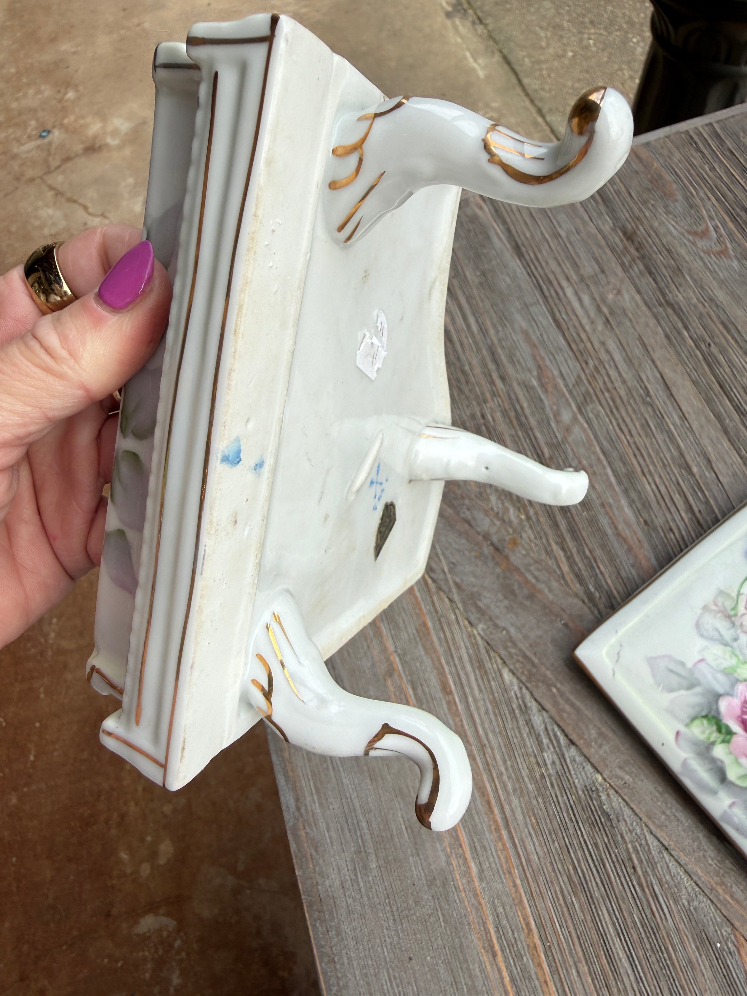 Decorative shelf with swan design held by a hand on a wooden surface