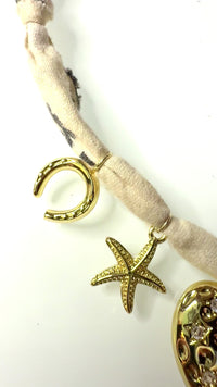 Mandriana, scarf necklace, heart charm necklace, handmade charm jewelry, beachy boho accessory, cross charm necklace, starfish necklace, symbolic jewelry, neutral bandana necklace, one of a kind statement piece, artisanal jewelry, boho chic accessories, charm scarf necklace, textured heart necklace