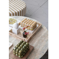 Decorative items on a marble table including a box of round objects, a vase with flowers, and a spherical object.