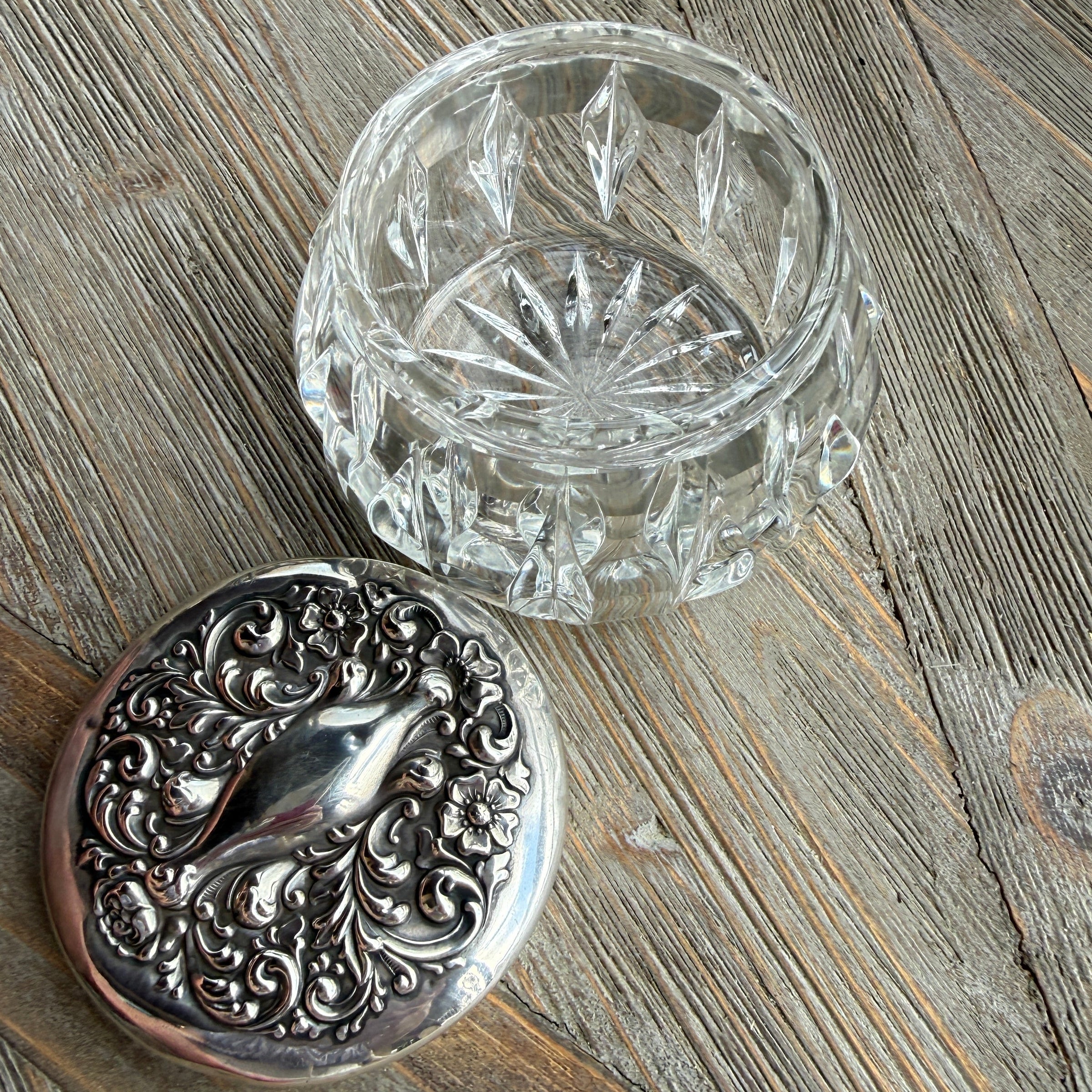 Silver decorative lid and clear glass container on a wooden surface
