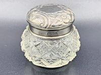 Decorative glass jar with silver lid on a gray background