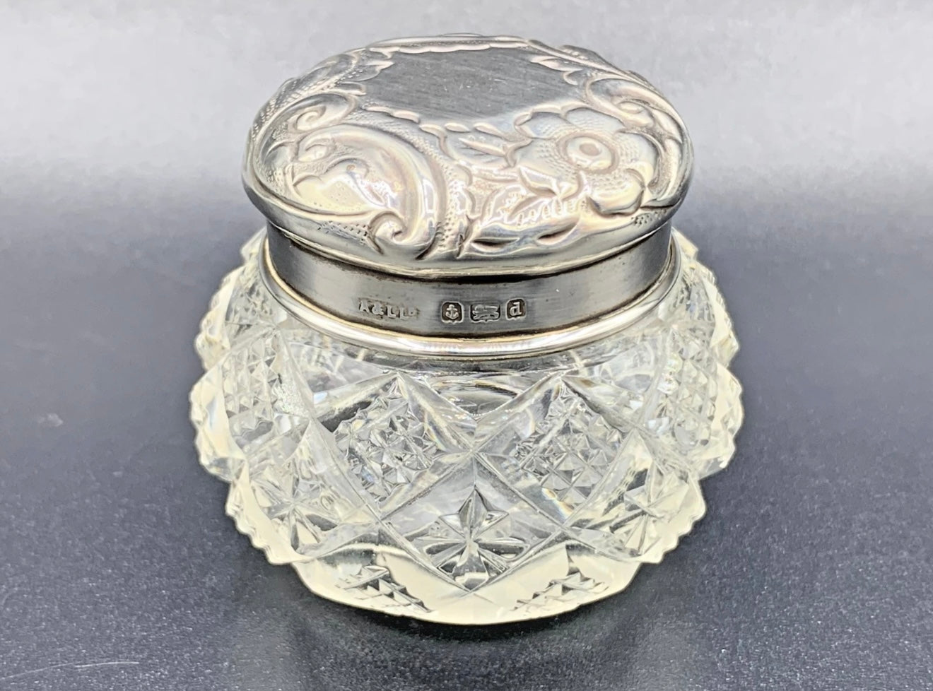 Decorative glass jar with silver lid on a gray background
