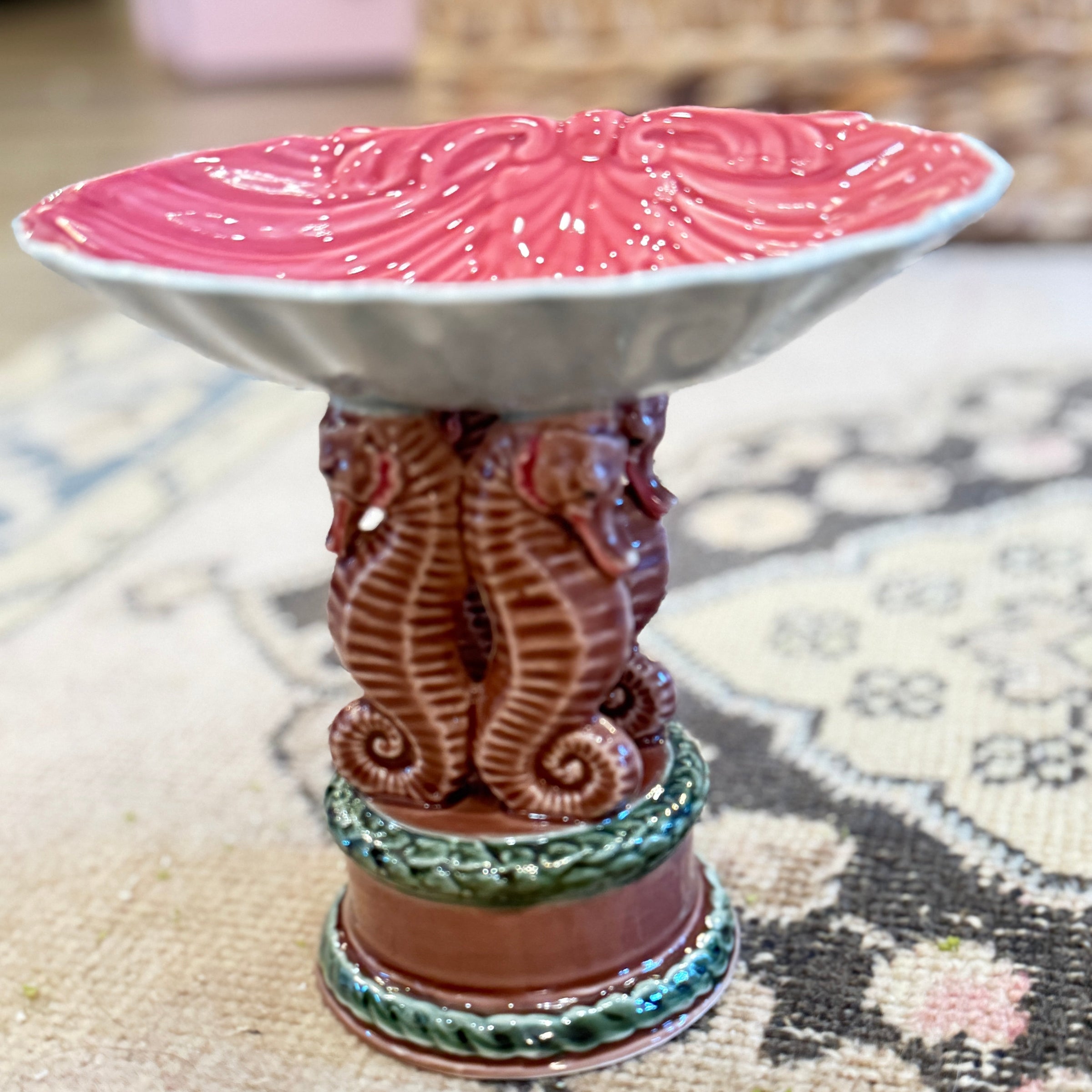 Decorative ceramic piece with pink top and detailed base on a patterned surface