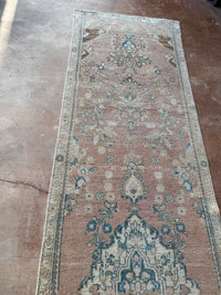 One-of-a-kind vintage Persian runner rug measuring approximately 2'11" x 12'5" with a faded dusty rose ground, blue and turquoise medallion motifs, ivory border and timeworn details.