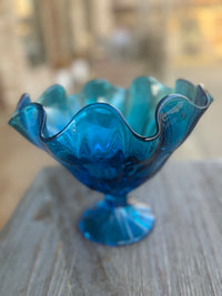 Blue glass bowl with wavy edge on a wooden surface