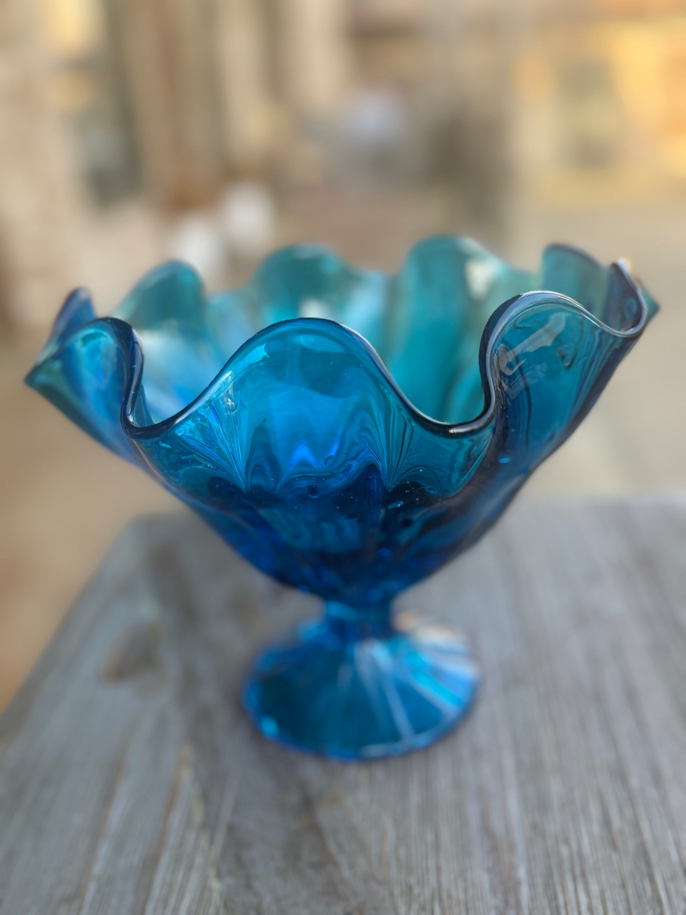 Blue glass bowl with wavy edge on a wooden surface