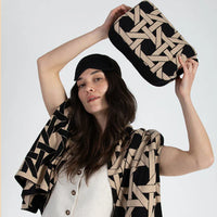 Woman holding a geometric-patterned bag and scarf against a white background