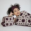 Woman wearing a patterned headband and blanket, holding a matching pouch against a white background
