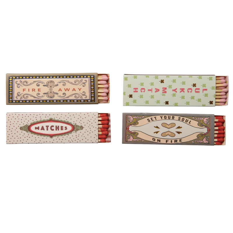 Four matchboxes with decorative labels on a white background