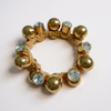 Bracelet with gold beads and crystal-like stones on a light pink background