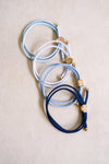 Set of blue and white hair ties with gold accents on a beige background