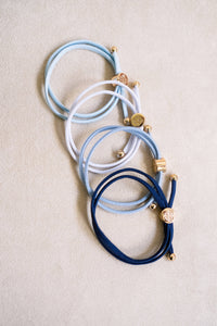 Set of blue and white hair ties with gold accents on a beige background