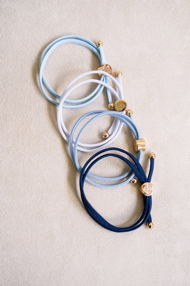 Set of blue and white hair ties with gold accents on a beige background