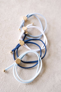 Set of blue and white bracelets with gold accents on a beige surface