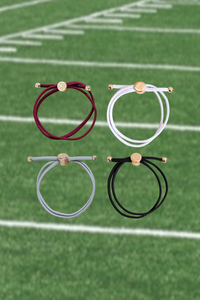 Four hair ties in red, white, gray, and black on a football field background