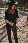 Person in cowboy attire holding a rope in an outdoor setting