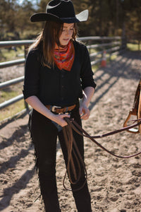 Person in cowboy attire holding a rope in an outdoor setting