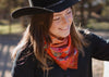 Woman wearing a black hat and colorful scarf outdoors