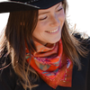 Woman wearing a colorful scarf and black hat, smiling outdoors.