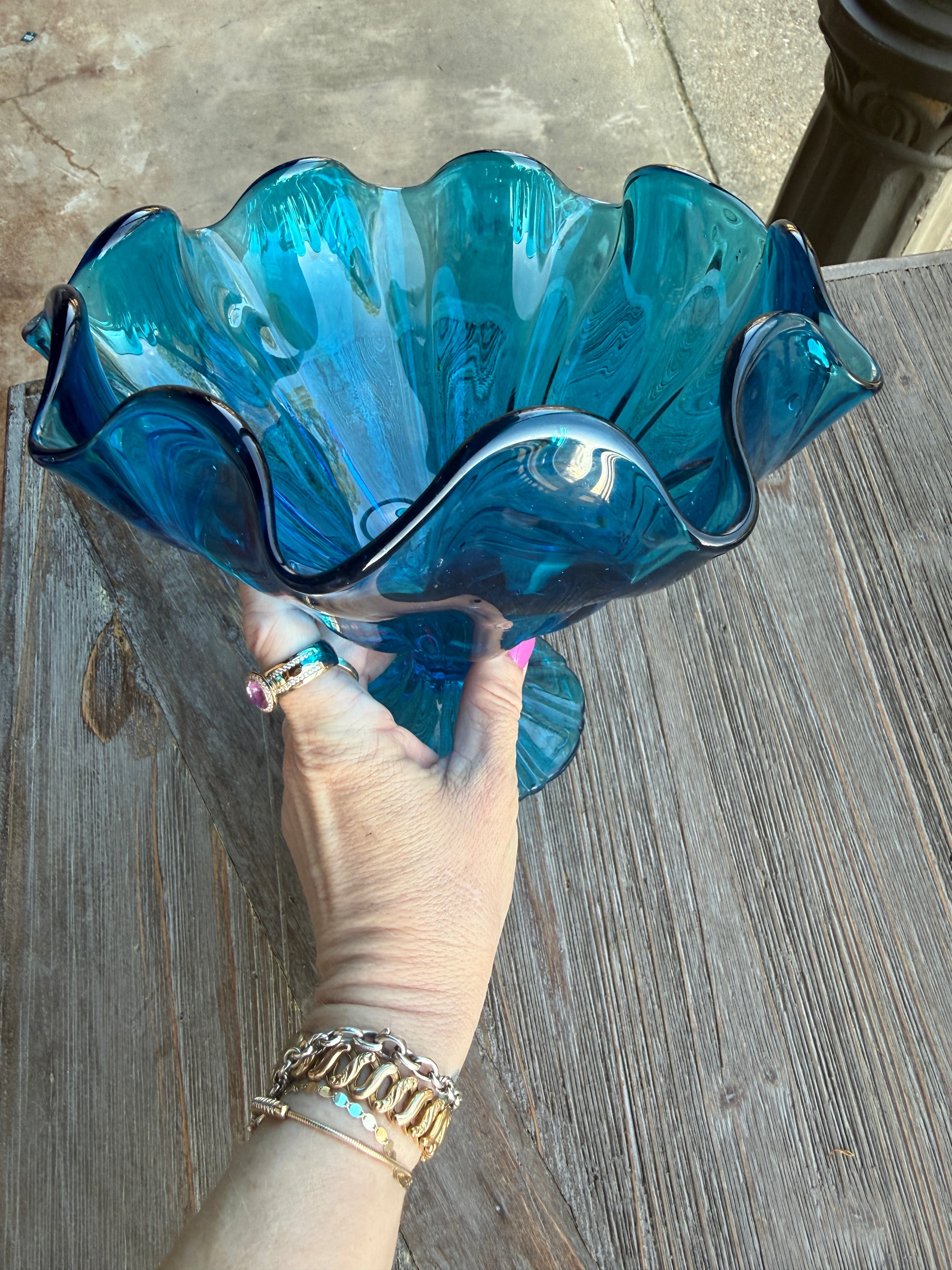 Hand holding a blue glass dish on a wooden surface