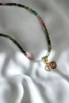 Necklace with multicolored beads and a pendant on a white fabric background