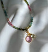 Necklace with multicolored beads and a pink pendant on a white background